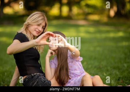 Mother and daughter making a heart shape with hands in the park. Stock Photo