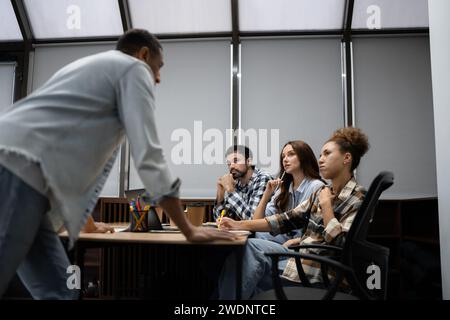 Group of diverse businesspeople using a laptop while working together in a modern workspace. Stock Photo