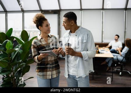 Group of diverse businesspeople using a laptop while working together in a modern workspace. Stock Photo