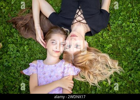 Mother and daughter lying on green grass. Stock Photo