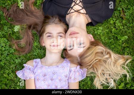 Mother and daughter lying on green grass. Stock Photo