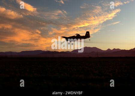 Single engine crop duster airplane flying low over field in California'ss imperial Valley at sunset Stock Photo