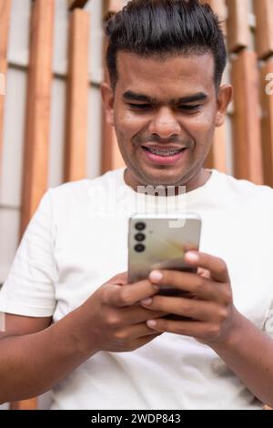 Latin Man with Braces Using Smartphone Stock Photo