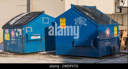 Two blue garbage dumpsters with graffiti on them in a parking lot in Swissvale, Pennsylvania, USA Stock Photo