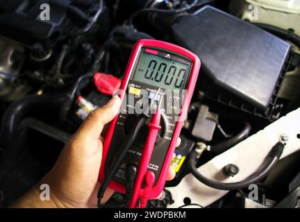 Digital multimeter in the hands of mechanics for measuring car electrical systems , Car maintenance service concept Stock Photo