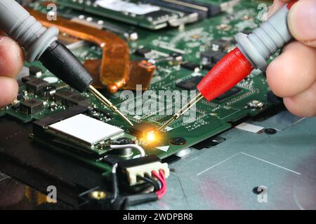 Technician checking electronics part on circuit board with probe of digital multimeter , Electronics part repair concept Stock Photo