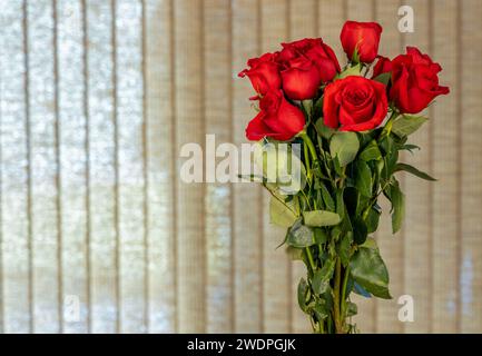 A Bouquet of a dozen red roses in a glass insert on the table Stock Photo