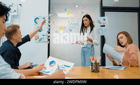 Closeup of young handsome caucasian raising hand and asking questions while young beautiful leader present business plan by using mind map and Stock Photo