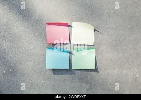 Four multicolored sticky notes in sunlight on gray concrete texture Stock Photo