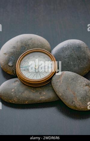 An antique brass compass laying on top of rocks. Stock Photo