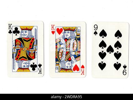 Vintage playing cards showing a pair of kings and a black nine isolated on a white background. Stock Photo