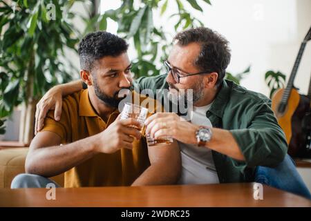 Best friends, supporting each other, drinking whiskey and talking. Discussing problems and drowning sorrows in alcohol. Concept of male friendship Stock Photo