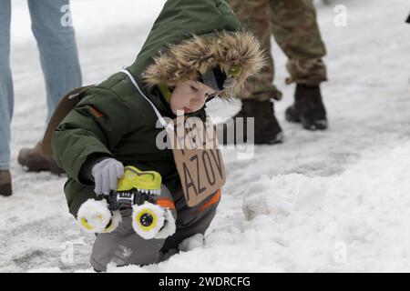 KYIV, UKRAINE - JANUARY 21, 2024 - A little boy with a placard plays with a toy car in Kontraktova Square during the Don’t Be Silent! Captivity Kills! Let’s Unite for the Lives of Heroes initiative to remind about the Ukrainian military personnel who are being kept in Russian captivity, Kyiv, capital of Ukraine. Stock Photo
