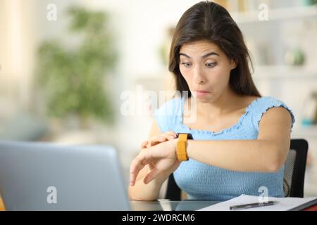 Perplexed student checking smartwatch content at home Stock Photo