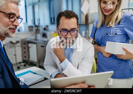 Pharmaceutical sales representative presenting new product to doctors in holding tablet. Presenting new pharmaceutical product, drugs, medication. Stock Photo