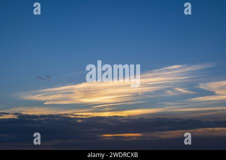 Sky at sunset background cloudscape with sunlit clouds and darker below. Stock Photo