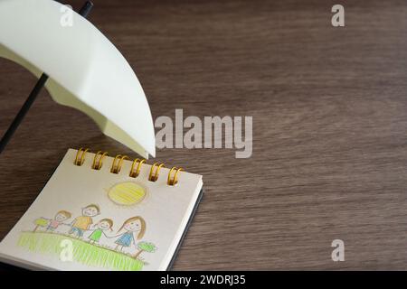 A child's drawing of a family under an umbrella with copy space. Family protection and insurance coverage concept. Stock Photo