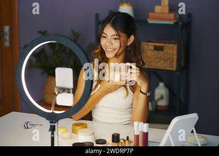 Smiling girl filming blog, showing new cosmetics she bought online Stock Photo