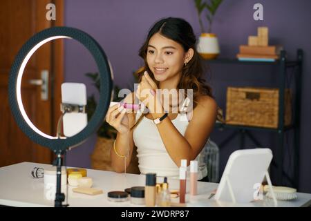 Smiling teenage girl showing swatches of liquid lipsticks when filming video for her beauty blog Stock Photo