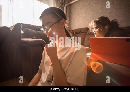 Asian students in glasses and headphones preparing for exams at home Stock Photo