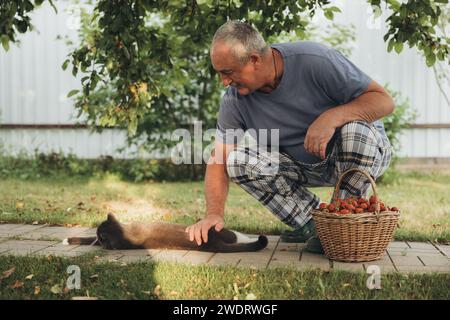 Senior man is petting a cat in his garden Stock Photo