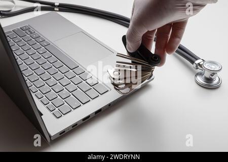 Hand with tools on laptop and stethoscope. Technical support concept Stock Photo