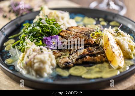 Grilled trout fillet with mashed potatoes and lemon sauce on a restaurant plate. Stock Photo