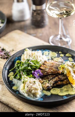 Grilled trout fillet with mashed potatoes and lemon sauce on a restaurant plate. Stock Photo