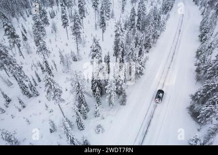 Aerial view of a car driving through the snow covered forest on icy road, Akaslompolo, Finnish Lapland, Finland, Scandinavia, Europe Stock Photo