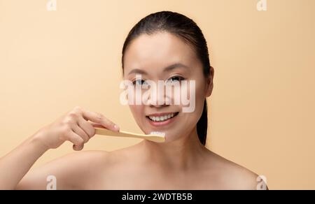 Cheerful millennial chinese woman with perfect smile, brushing teeth with toothbrush Stock Photo