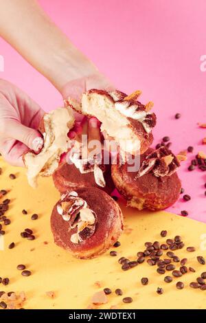 Tiramisu doughnut with coco bean topping filled with custard cream. Hand holding. Stock Photo