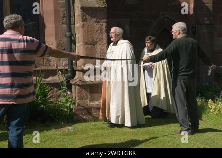 Revd prebendary Edward Ward leads the congregation around the Church in the Clypping Ceremony St Peters Church, Edgmond, Shropshire Uk 2015.  The congregation hold hands in a circle around the whole of the church, if they can, they did just with the use of belts and ropes to complete the unbroken circle.  England 2010s HOMER SYKES Stock Photo