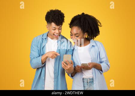 A young woman and man share a joyful moment looking at a smartphone together Stock Photo
