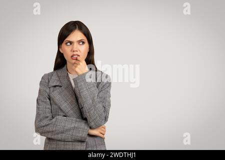 Woman in plaid blazer pondering, looking sideway at free space Stock Photo