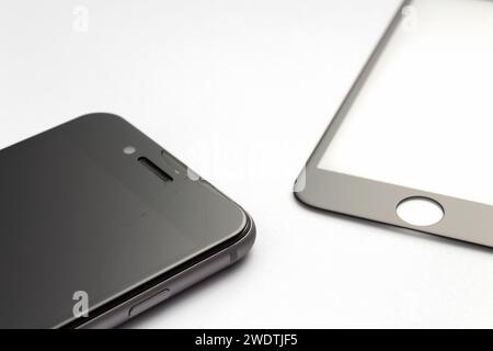 Smartphone with cracked protective glass on white background. Protective glass replacement. Stock Photo