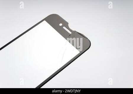 Cracked protective glass for smartphone on white background. Stock Photo
