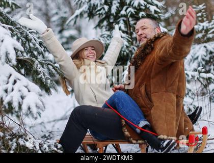 couple in love having fun spending winter time, sitting and hugging on sled Stock Photo