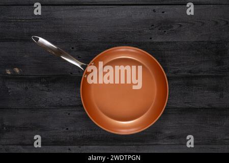 Round fry pan on a weathered black wood texture background. Non-stick, ceramic coated cooking technology. Stock Photo