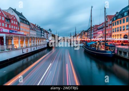 Twilight Symphony at Nyhavn: Long Exposure Captures Light Trails on Water Amidst the Iconic Colorful Buildings of Copenhagen Stock Photo