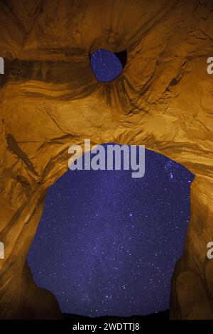 The Milky Way through the Big Hogan Arch at night in the Monument Valley Navajo Tribal Park in Arizona. Stock Photo