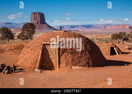 Traditional Navajo hogan in front of Mitchell Butte in the Monument Valley Navajo Tribal Park in Arizona.  A sweat lodge is a right. Stock Photo