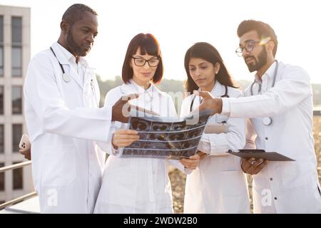 Multicultural doctors discussing patient's CT scan outside the hospital. Stock Photo