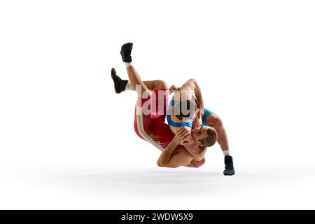 Two strong wrestlers in blue and red wrestling uniform fighting and making hip throw in motion against white studio background. Stock Photo