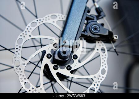 Part of the bicycle's braking system. Grey metal brake disc and brake pads on road bike, close up. Stock Photo