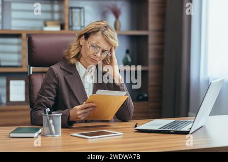 A professional senior woman engrossed in work at her home office, embodying dedication and remote business management. Stock Photo