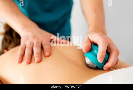 Skilled massage therapist's hands doing back massage with special massage accessories in a massage parlor Stock Photo