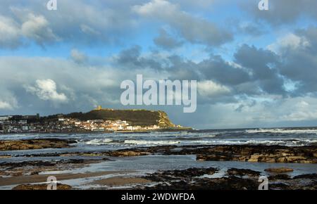 The Tide goes out during a wintery gale giving a view of the Castle Headland from the Black Rocks in Scarborough's South Bay Stock Photo