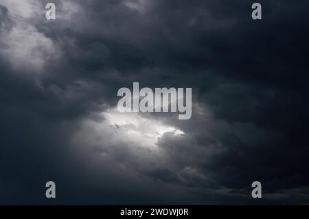 Gray clouds before thunderstorm. Gleam of light in black clouds before the storm. Stock Photo