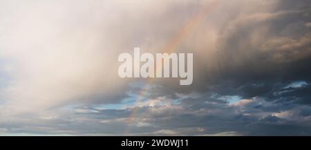 Rainbow in the cloudy rainy sky Stock Photo
