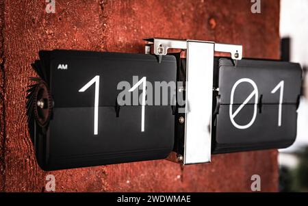 Flip black clock with eleven o'clock time on panel closeup. Clock with hours and minutes numbers Stock Photo